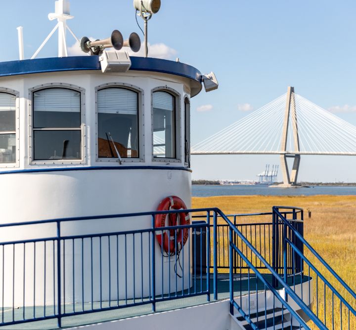 SpiritLine Cruises boat docked by grass and a bridge.